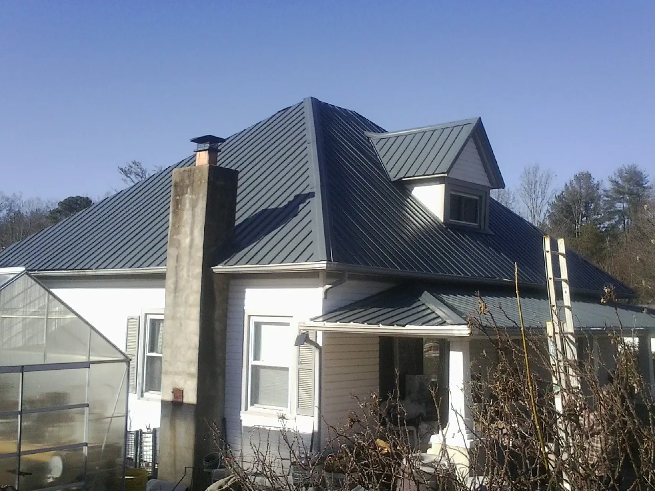 Dark blue standing seam metal roof on a white farmhouse with dormer — Slate & Tile Roof Repair by Roofing Brothers in Gold Canyon