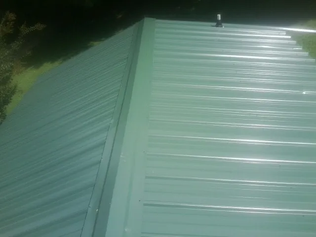 New green metal panels meeting at the ridge of a roof — Flat Roof Repair work by our crew in Gold Canyon