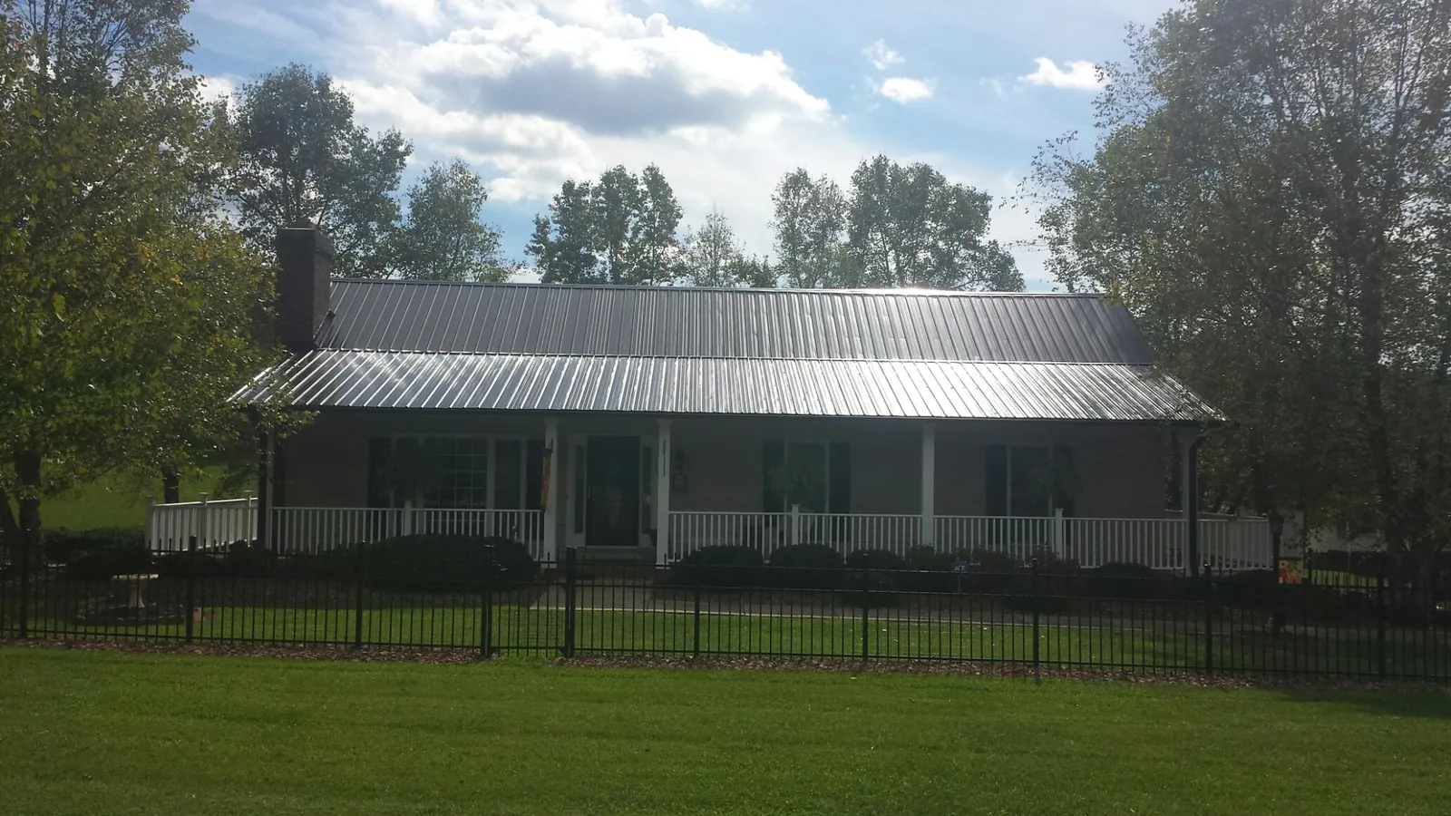 Gray metal roof on a brick ranch with a full width front porch — Gutter Guard Installation work by our crew in Gold Canyon