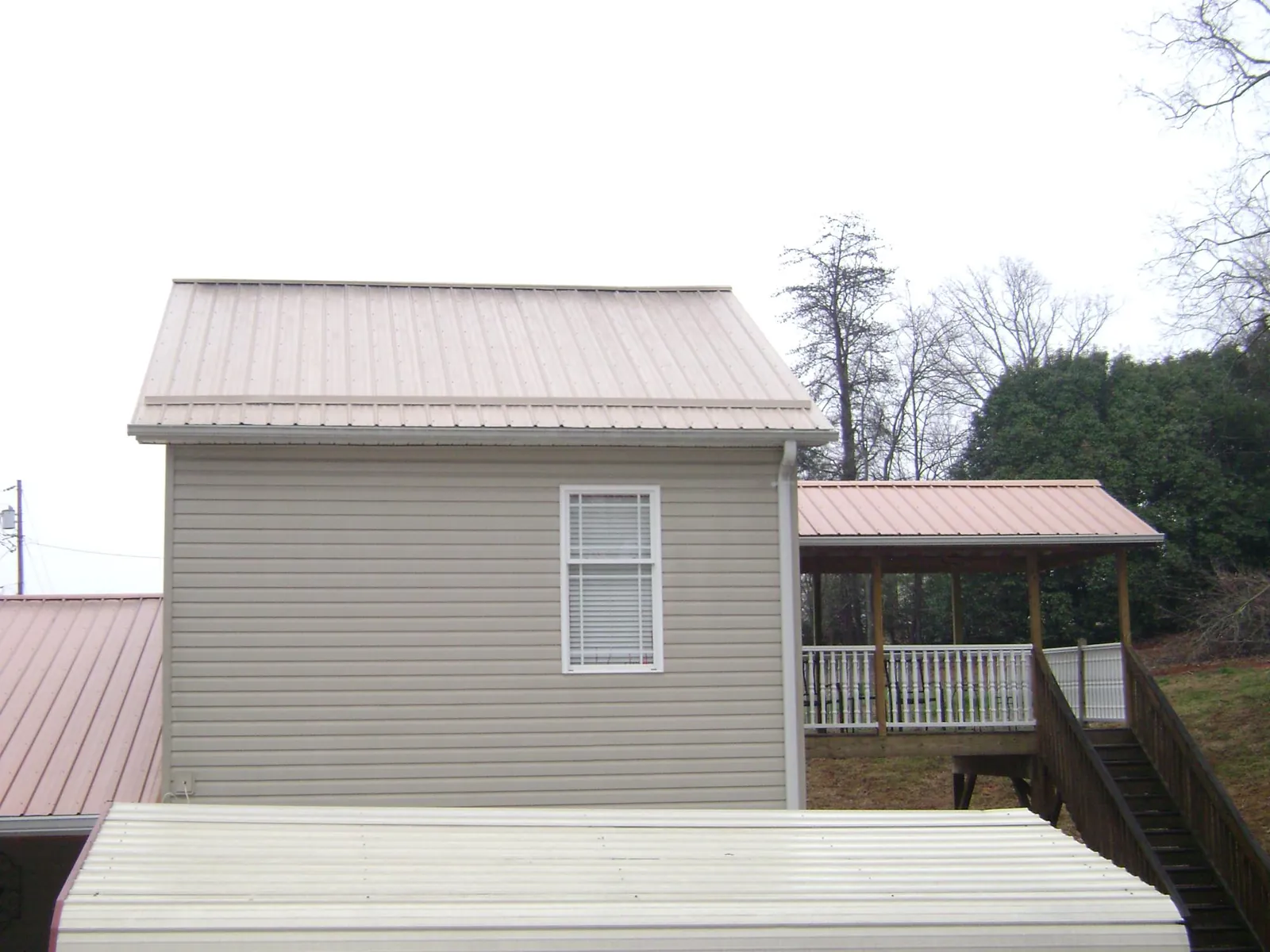 Tan metal roofs on a two story addition and attached porch, from a Roof Replacement job in Gold Canyon