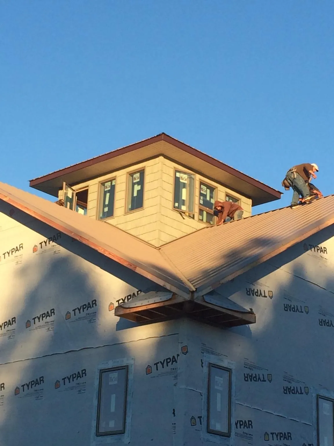 Roofers working around a rooftop cupola on a new metal roof at sunset — Roof Waterproofing in Gold Canyon by Roofing Brothers